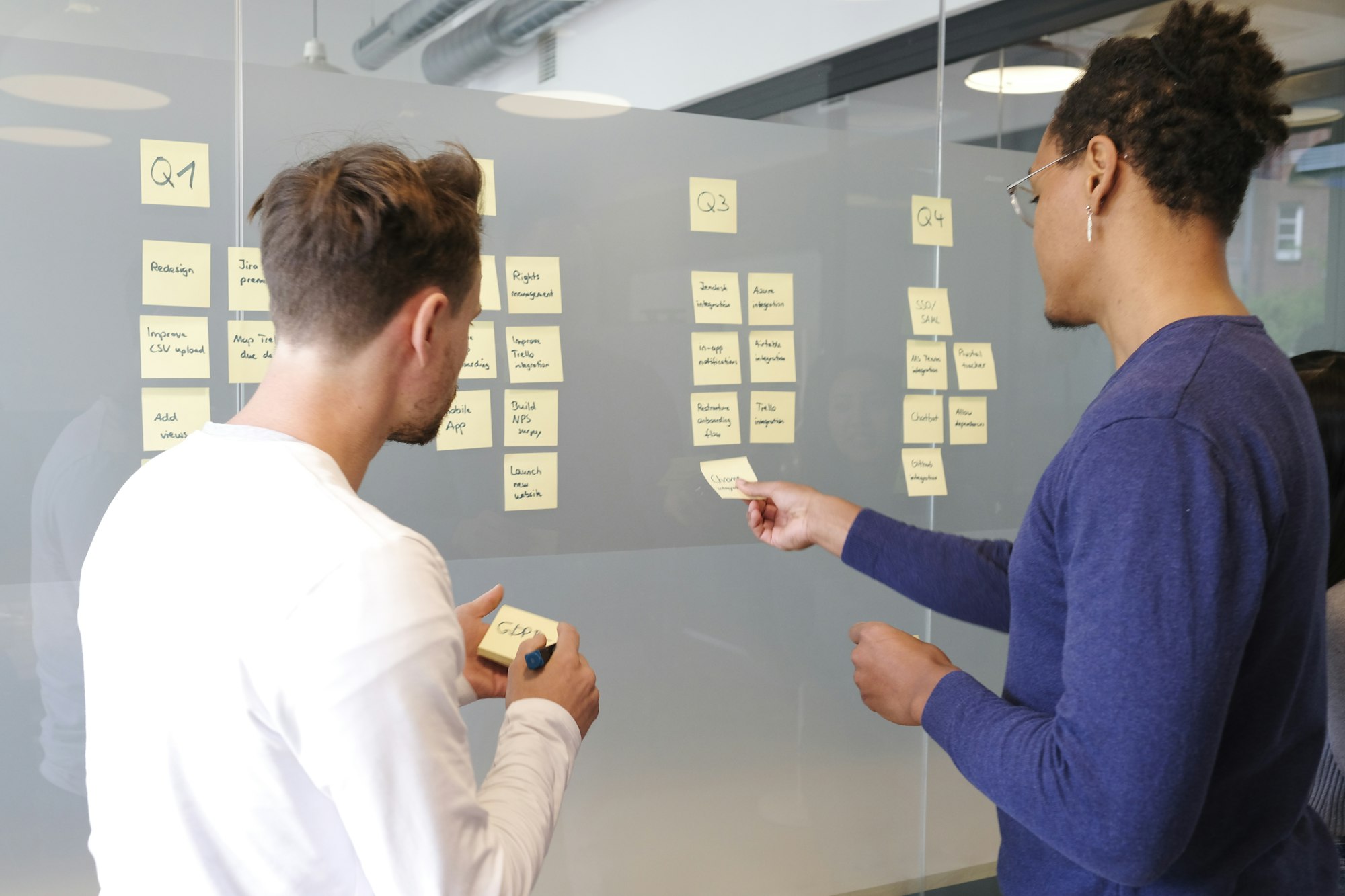 Dos personas analizando información en un muro de trabajo